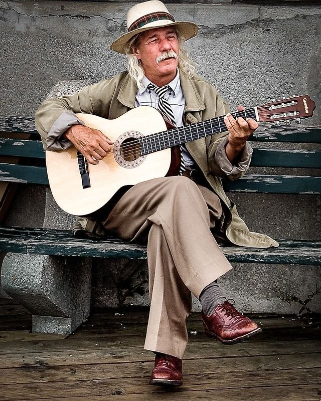 Hombre mayor tocando canciones en su guitarra clásica de cuerdas de Nylon