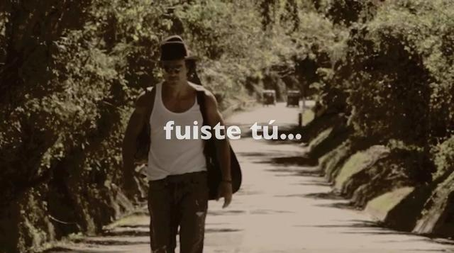 Artista Ricardo Arjona caminando en una carretera con una guitarra en la espalda junto con la letra de la canción